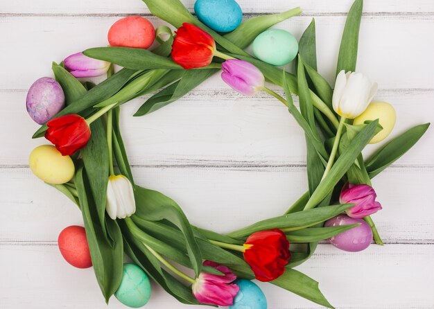 Frame made from Easter eggs and tulips on table