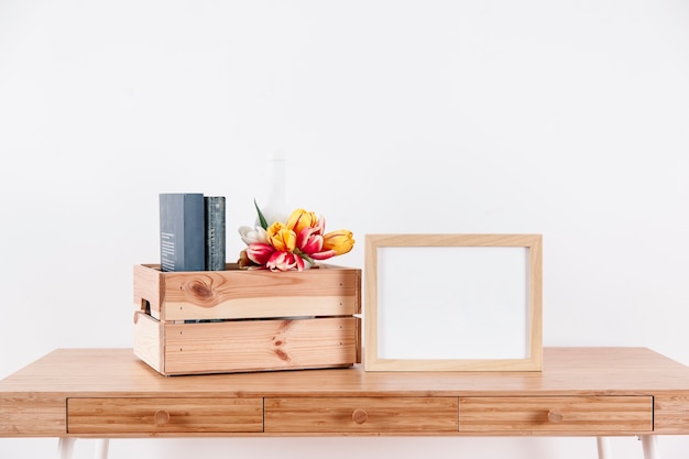 Frame near box with flowers and books