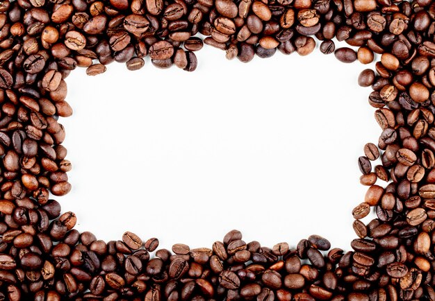 Frame of roasted coffee beans on white background top view