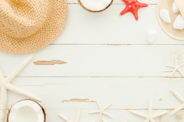 Frame of straw hat, sea stars and coconuts