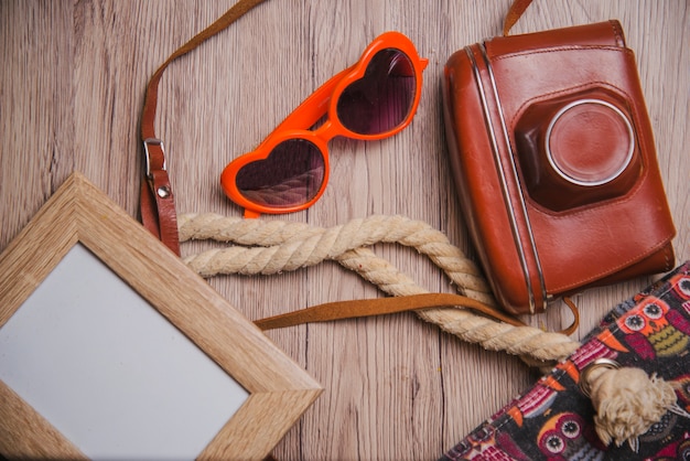 Free photo frame, sunglasses and camera on wooden surface