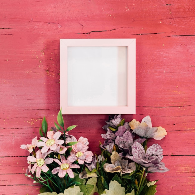 Frame with flower bouquets on pink wooden background