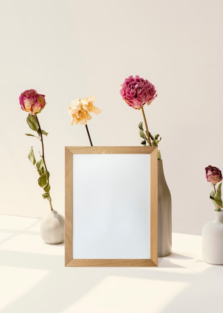 Free photo frame with flowers against white minimal wall