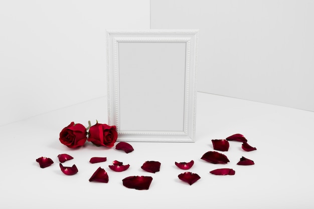 Frame with red roses on white table