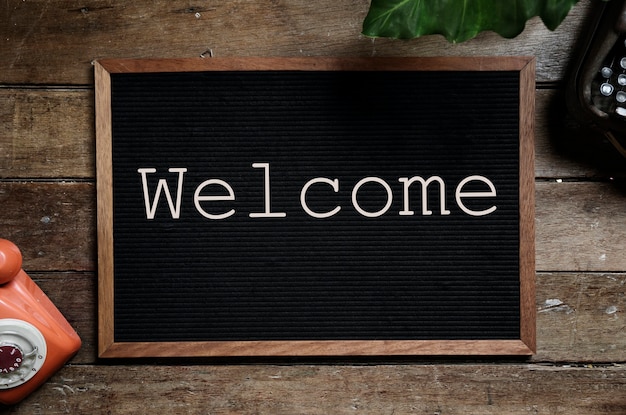 Frame with word Welcome on wooden table