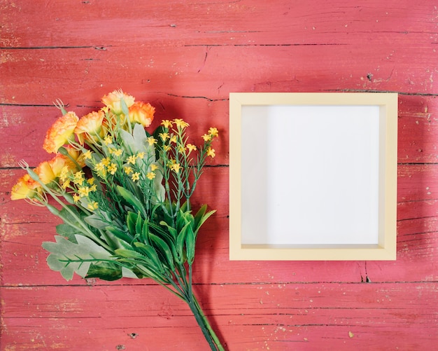 Frame with yellow flowers on pink wooden background