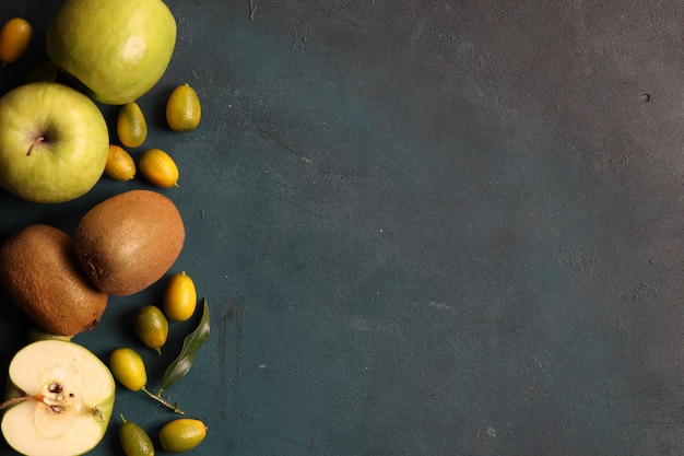 Framing with green apples, kiwi and kinkans on gray background