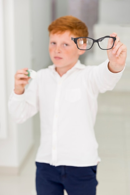 Freckle boy holding eyeglasses and contact lenses container
