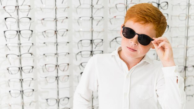 Freckle boy with black eyeglasses posing in optics shop