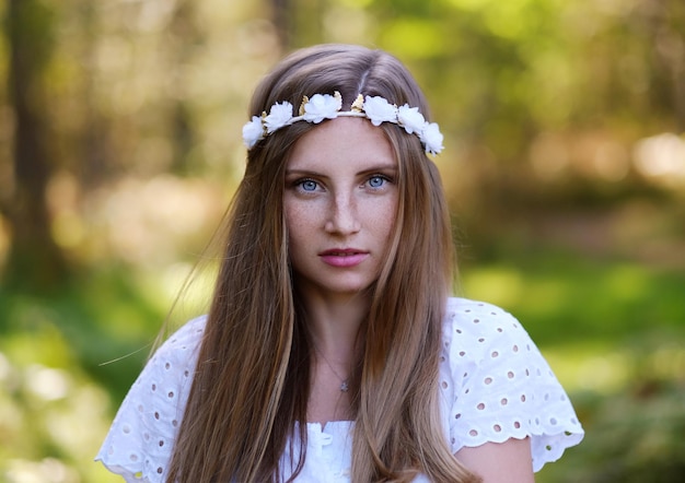 Freckled woman with circlet of flower on her head portrait in autumn forest in a day light.