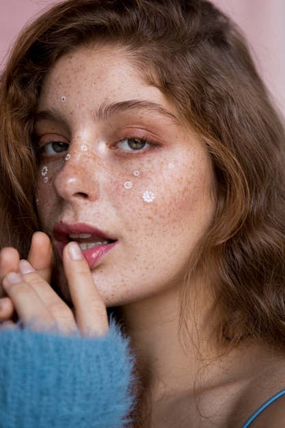 Freckled woman with white flowers on her face close-up