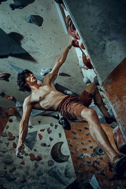 Free climber climbing artificial boulder indoors