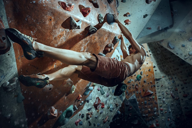 Free climber climbing artificial boulder indoors