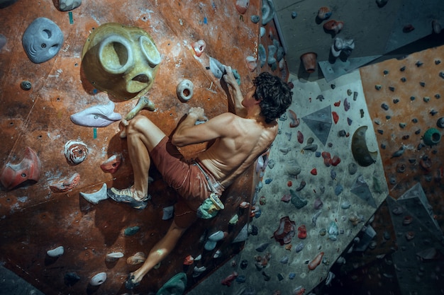 Free climber climbing artificial boulder indoors