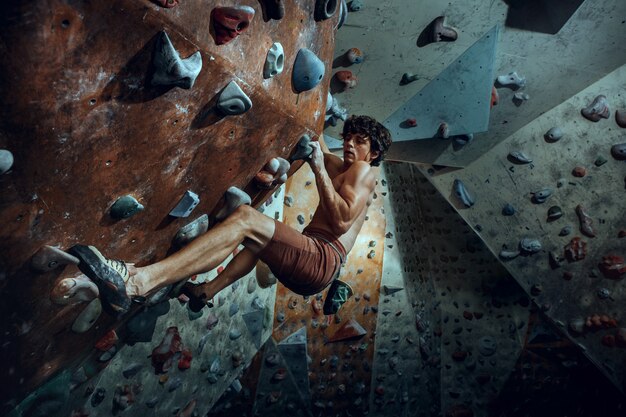 Free climber climbing artificial boulder indoors