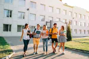 Foto gratuita tempo libero di studenti, ritmo di vita del campus universitario. cinque studenti amichevoli stanno camminando