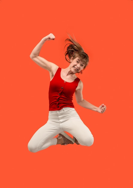 움직이는 자유. 꽤 행복 한 젊은 여자 점프와 오렌지에 대 한 몸짓의 공중 샷