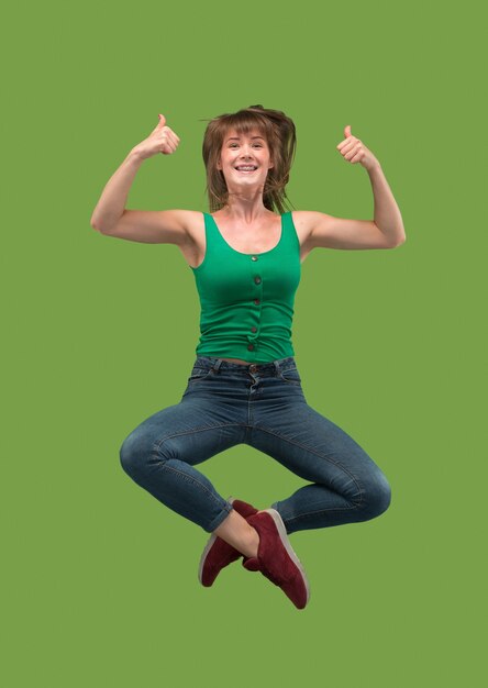 Freedom in moving. Mid-air shot of pretty happy young woman jumping and gesturing on green