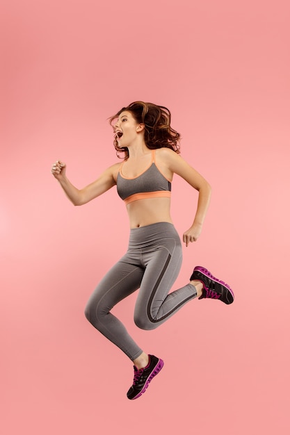 Freedom in moving. Pretty young woman jumping against orange background