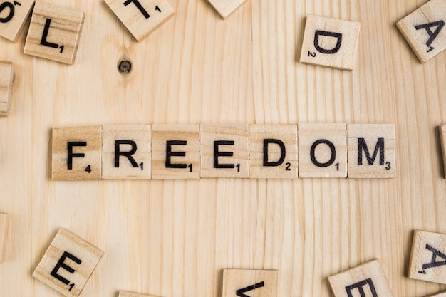 Free photo freedom word on wooden tiles