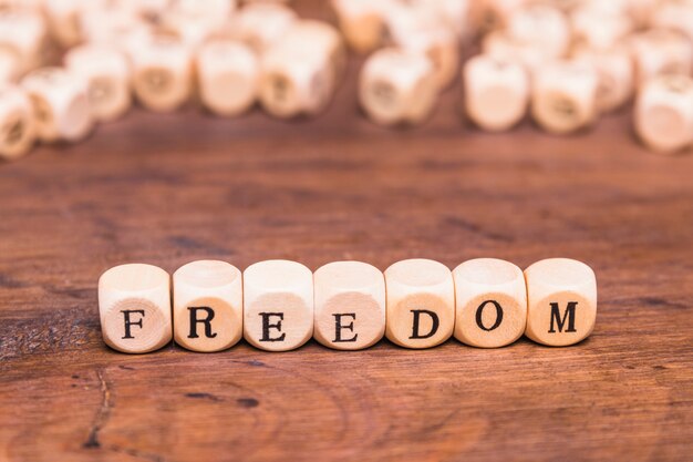 机の上の木製のサイコロに書かれた自由の言葉