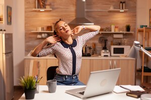 Free photo freelance woman stretching arms because of exhaustion while working overtime from home. employee using modern technology at midnight doing overtime for job, business, busy, career, network, lifestyle