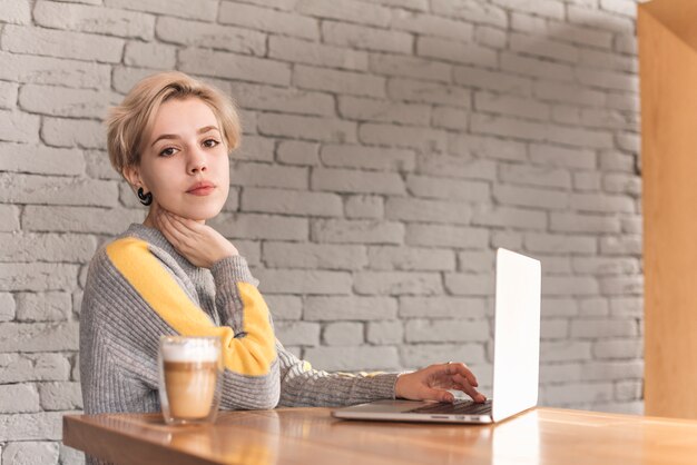 無料写真 コーヒーショップでノートパソコンを扱うフリーランスの女性