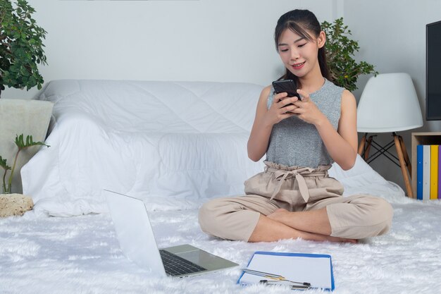 Freelance, working from home - young woman is using the phone while working at living room.