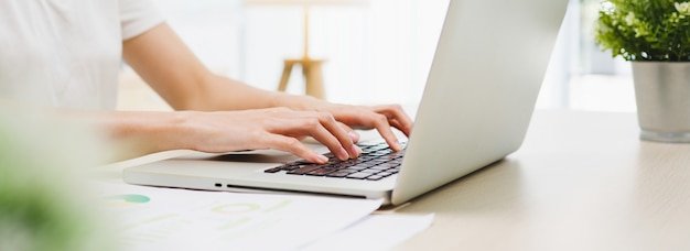 Free photo freelance young asian businesswoman casual wear using laptop working in living room at home.