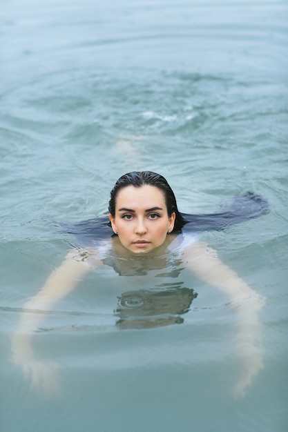 Nuoto in stile libero nel mare in costume da bagno bianco