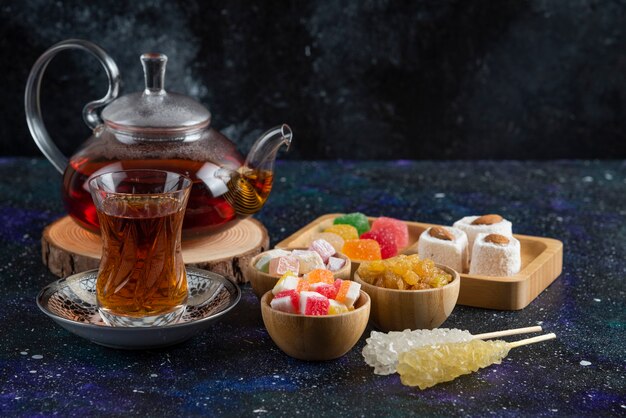 Fregrant tea with sweet candies on blue surface
