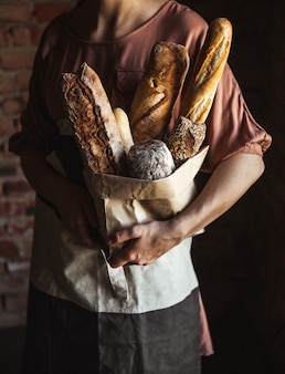 黒​の​背景​に​女性​の​手​で​フランス​パン​。​自家製​ベーキング