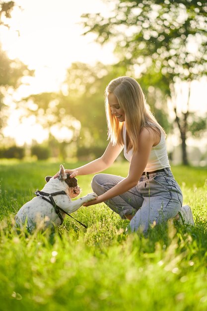 French bulldog giving paw to female owner in park