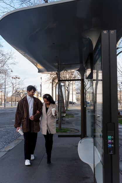 French couple walking to the station to take the bus and drinking coffee