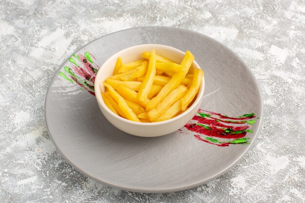 french fries inside white little plateo on grey
