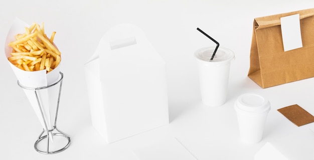 Free photo french fries; parcel and disposal cup on white background