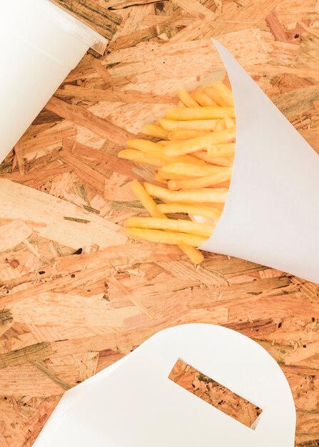 French fries in white cone on wooden textured backdrop