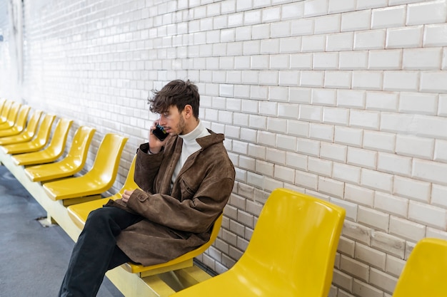 Foto gratuita uomo francese che aspetta il treno della metropolitana e parla sullo smartphone