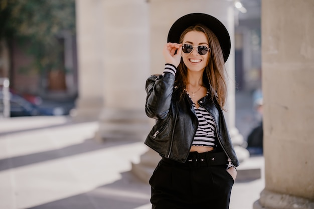 Free photo french pretty young brown-haired girl in a leather jacket, black hat on the city promenade