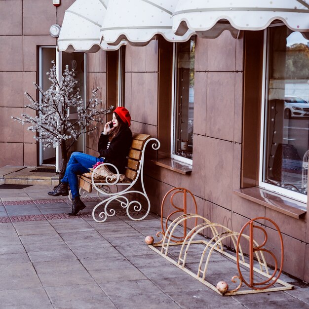 French woman in a red beret on a street bench