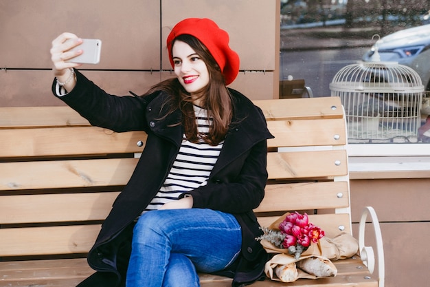 French woman in a red beret on a street bench