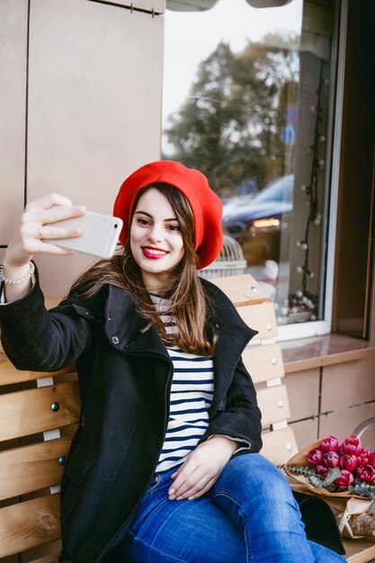 French woman in a red beret on a street bench