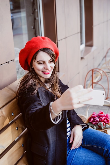 French woman in a red beret on a street bench