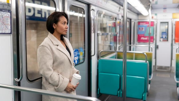 French woman riding the subway train and drinking coffee