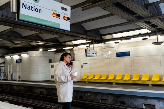 French woman waiting for the subway train and drinking coffee