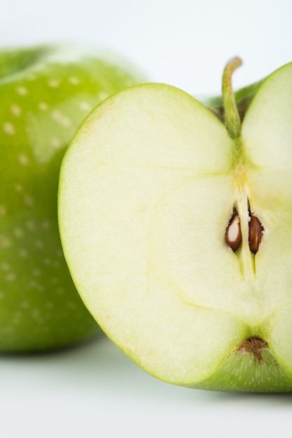 Свежий яблочный зеленый спелые половину вырезать изолирован на белом столе