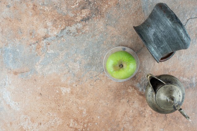 A fresh apple with an ancient cups on marble table.