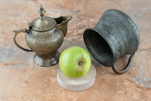 A fresh apple with an ancient cups on marble