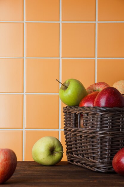 Fresh apples in a basket on a orange tile background. side view. space for text