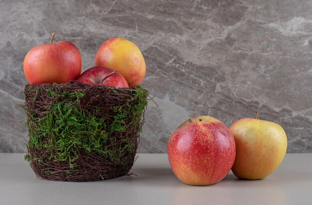 Fresh apples in and next to a bowl on marble 